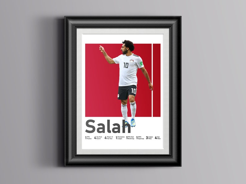 K&ouml;nnte beinhalten: Ein gerahmtes Poster mit einem Foto von Mohamed Salah, einem &auml;gyptischen Profi-Fu&szlig;baller, der ein wei&szlig;es Trikot mit der Nummer 10 tr&auml;gt. Das Poster hat einen roten Hintergrund und den Text "Salah" in Wei&szlig;. Das Poster enth&auml;lt auch eine Liste von Salahs Leistungen, darunter "1x FIFA Puskas Award", "4x Premier League", "4x Spieler des Jahres", "1x Champions League", "1x FIFA Club World Cup", "3x UEFA Super Cup" und "4x Pokaltitel".
