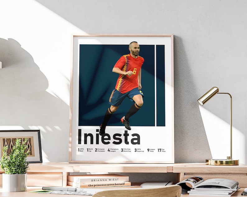 K&ouml;nnte beinhalten: Ein Poster mit einem Fu&szlig;ballspieler in einem rot-gelben Trikot mit der Nummer 6 auf dem R&uuml;cken. Der Spieler rennt mit dem Ball. Das Poster zeigt den Text "Iniesta" in gro&szlig;en schwarzen Buchstaben und eine Liste der Titel und Troph&auml;en, die der Spieler gewonnen hat.