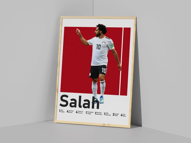 K&ouml;nnte beinhalten: Ein Poster mit einem Foto von Mohamed Salah, einem &auml;gyptischen Profi-Fu&szlig;baller, der ein wei&szlig;es Trikot mit der Nummer 10 tr&auml;gt. Das Poster hat einen roten Hintergrund und den Text "Salah" in Schwarz. Das Poster enth&auml;lt auch eine Liste von Salahs Leistungen, darunter "FIFA Puskas Award", "Top-Torsch&uuml;tze", "Spieler des Jahres", "Champions League", "FIFA Club World Cup", "UEFA Super Cup", "Liga-Titel" und "Pokal-Titel".