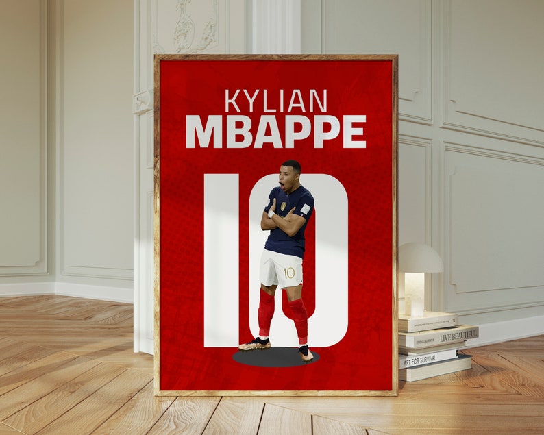 以下が含まれることがあります： 白い数字の10と白い文字で「KYLIAN MBAPPE」と書かれた赤いポスター。青いユニフォームを着て背番号10のサッカー選手の画像がポスターの中央に配置されている。