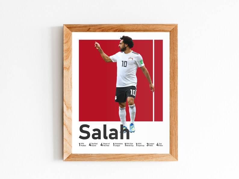 K&ouml;nnte beinhalten: Ein gerahmtes Poster mit einem Foto von Mohamed Salah, einem professionellen Fu&szlig;ballspieler, in einem wei&szlig;en Trikot mit der Nummer 10. Das Poster hat einen roten Hintergrund und den Text "Salah" in fetten schwarzen Buchstaben. Das Poster enth&auml;lt auch eine Liste von Salahs Leistungen, darunter "1 FIFA Puskas Award", "4 Premier League Titel", "4 Spieler des Jahres Auszeichnungen", "1 Champions League Titel", "1 FIFA Club World Cup", "3 UEFA Supercup", "3 League Cup Titel" und "4 FA Cup Titel".
