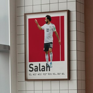 K&ouml;nnte beinhalten: Ein Poster mit einem Foto von Mohamed Salah, einem professionellen Fu&szlig;ballspieler, der ein wei&szlig;es Trikot mit der Nummer 10 tr&auml;gt. Der Hintergrund ist rot und der Text "Salah" ist in Schwarz unter dem Foto gedruckt. Das Poster enth&auml;lt auch eine Liste von Salahs Leistungen, darunter "1 Premier League", "4 Champions League", "1 FIFA Club World Cup", "3 Super Cup" und "4 Africa Cup of Nations".