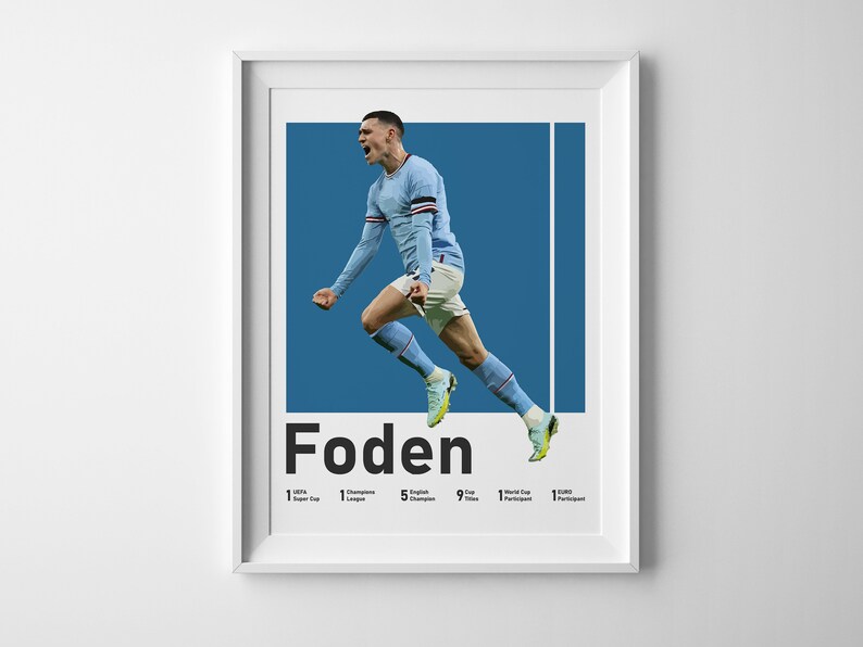 May include: A blue and white poster featuring a photo of a footballer in mid-air celebrating a goal. The player is wearing a light blue shirt with white accents. The poster has the text "Foden" in bold black letters and lists the player's achievements: 1 Premier League, 1 Champions League, 5 English Championships, 9 Premier League Goals, 1 World Cup Participant, 1 Euro Participant.