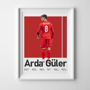 May include: A poster featuring a soccer player wearing a red jersey with the number 8 on the back. The player is standing on a red background with the name "Arda G&uuml;ler" in black text below. The poster also includes a list of the player's accomplishments.