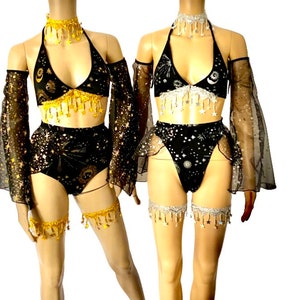 May include: Two matching black and gold celestial-themed lingerie sets. Each set includes a halter top, high-waisted bottoms, arm sleeves, and leg garters. The tops and bottoms are adorned with star and moon patterns, and the sets feature dangling gold or silver accents.