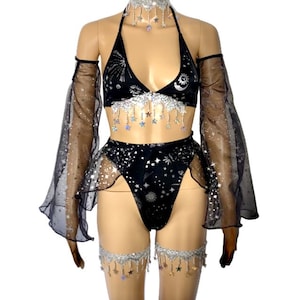 May include: Black lingerie set with a celestial theme. The set includes a halter top, high-waisted bottoms, arm sleeves, a choker, and leg garters. The fabric is adorned with silver stars and celestial patterns, with dangling star accents.