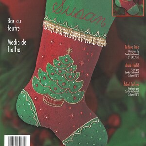 May include: A red and green felt Christmas stocking kit with the name "Susan" embroidered in red. The stocking features a green Christmas tree design and is 18 inches (45.7 cm) long. The kit is designed by Sandy Garbrandt.