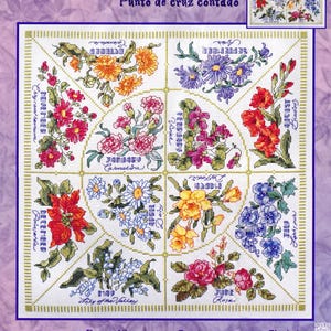 May include: A Bucilla counted cross stitch kit featuring a floral design. The kit includes a pattern with flowers representing each month, with text labels. The finished design is approximately 12.25 x 12.25 inches.