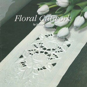 May include: A white fabric with a floral cutwork design. The fabric is embroidered with flowers and leaves. The image is titled "Floral Cutwork" by Janice Stewart.