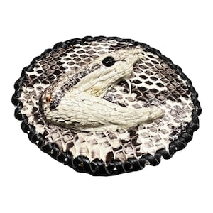 Peut inclure: Une boucle de ceinture en cuir noir avec un motif de peau de serpent blanc. Le serpent est enroul&eacute; sur lui-m&ecirc;me, la t&ecirc;te tourn&eacute;e vers le spectateur. La boucle est ronde et poss&egrave;de une bordure en cuir noir.