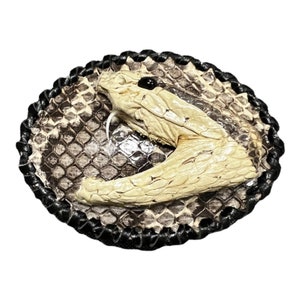 Peut inclure: Une boucle de ceinture en cuir marron et noir avec un motif de t&ecirc;te de serpent blanc. La t&ecirc;te de serpent est en relief et a un &oelig;il noir.