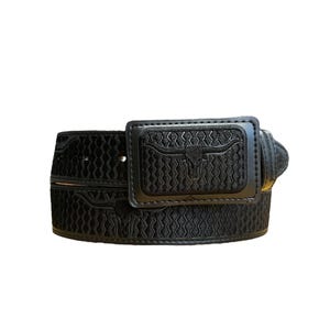 May include: A black belt featuring a rectangular buckle with an embossed longhorn steer head design. The strap is decorated with a repeating geometric wave pattern and additional longhorn steer head motifs, all rendered in a monochromatic black.