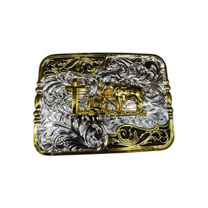 May include: A silver and gold belt buckle with an ornate design. The buckle features a horse and a cross.