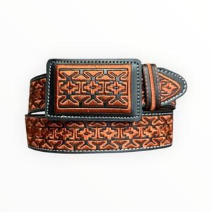 May include: A belt featuring a rectangular buckle and a strap, both decorated with a repeating geometric pattern in copper-colored thread against a black background. The edges of the buckle and the strap are finished with black stitching.