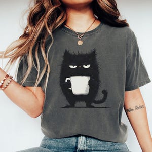 面白い黒猫のコーヒーシャツ、かわいい疲れた猫のTシャツ、マグカップを持った不機嫌な猫のグラフィックTシャツ、かわいい猫好きへのギフト、疲れた猫のコーヒーTシャツ