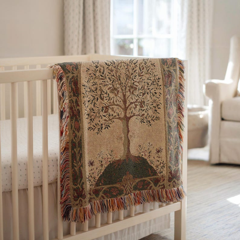 Peut inclure: Une couverture en tapisserie tiss&eacute;e avec un motif d'arbre drap&eacute;e sur un berceau blanc. La couverture pr&eacute;sente un motif d'arbre central en marron et vert, avec un fond beige et une frange color&eacute;e.