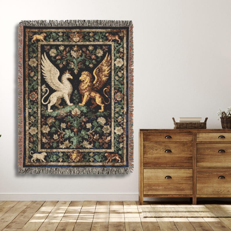May include: A tapestry throw blanket featuring a central design of a white griffin and a golden lion with wings, set against a dark background with floral and foliage patterns. The blanket has a fringed edge and is hung on a white wall.