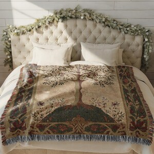 Peut inclure: Une couverture tiss&eacute;e avec un motif d'arbre dans les tons beige, vert et bordeaux. La couverture &agrave; franges est drap&eacute;e sur un lit avec des draps blancs. La t&ecirc;te de lit est recouverte d'un tissu neutre et d&eacute;cor&eacute;e d'une guirlande.