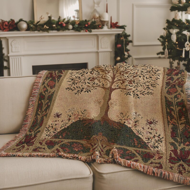 Peut inclure: Une couverture beige avec un motif d'arbre de vie, drap&eacute;e sur un canap&eacute;. La couverture pr&eacute;sente un motif de tapisserie d&eacute;taill&eacute; avec des accents verts, bruns et rouges. Le jet&eacute; a un bord &agrave; franges et est plac&eacute; dans un salon.