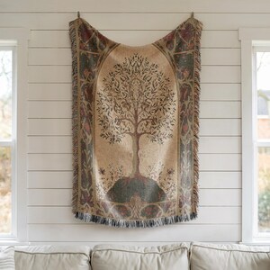 Peut inclure: Une tapisserie beige avec un motif d'arbre suspendue &agrave; un mur blanc. L'arbre est brun avec des feuilles vertes, sur un fond beige. La tapisserie a une bordure d&eacute;corative avec des franges.