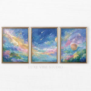 May include: Three framed art prints featuring a celestial theme. Each print showcases a vibrant watercolor painting of a colorful sky with planets, stars, and shooting stars. The frames are gold-colored, and the text "LUXE VIBE STUDIO" is at the bottom.