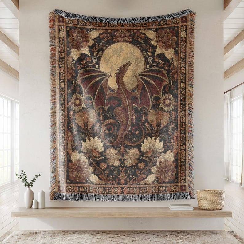 May include: A tapestry featuring a dragon with outstretched wings against a full moon. The dragon is brown and red, set against a dark background with floral and foliage patterns. The tapestry has a fringed border and is displayed on a wall.