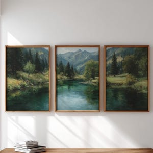 May include: A triptych of framed landscape paintings featuring a serene river flowing through a lush green valley with dense pine forests and towering mountains in the background, all rendered in deep shades of green, blue, and earthy brown tones.