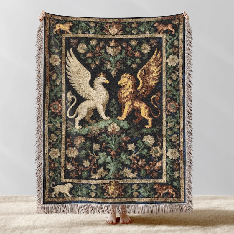 May include: A tapestry throw blanket featuring a griffin and a lion with wings facing each other. The blanket has a dark background with floral and foliage patterns in shades of green, brown, and gold. The edges are fringed.