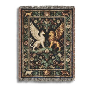 May include: Woven tapestry throw blanket featuring a central design of a winged griffin and a winged lion facing each other. The background is dark with floral and foliage patterns. The blanket has a fringed edge and a decorative border.