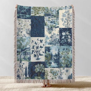 May include: A blue and white throw blanket with a patchwork design. The blanket features various squares with landscape and floral patterns in shades of blue and white. The edges have a fringed trim.