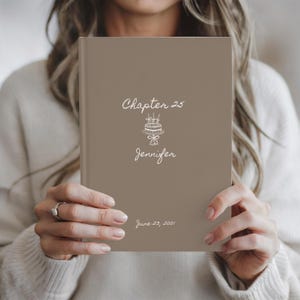 May include: A taupe-colored book with the text "Chapter 25" and "Jennifer" in a script font, along with a cake illustration. The date "June 23, 2001" is also printed on the cover.