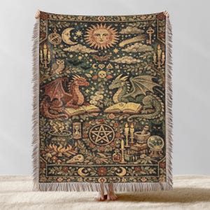 May include: A tapestry throw blanket with a detailed mosaic design. The artwork features a sun, moon, stars, dragons, and mystical symbols in shades of brown, green, and gold. The blanket has a fringed edge.