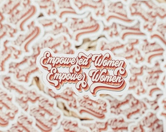 Puede incluir: Una colección de pegatinas con el texto "Empowered Women Empower Women" en una fuente retro. Las pegatinas tienen un fondo blanco con letras rojas y naranjas. Las pegatinas están sobre una superficie texturizada.