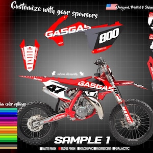 May include: A red and white motocross bike graphic kit with the word "GASGAS" printed on the side. The kit includes a number plate, front fender, rear fender, and swingarm graphics. The kit is designed for a GasGas motorcycle.