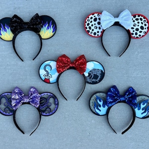 May include: Five decorative headbands with mouse ears. Each headband features a different design, including flames, Dalmatian spots, a pirate hook, an octopus, and flames. The headbands have bows in various colors, including black, white, red, purple, and blue.