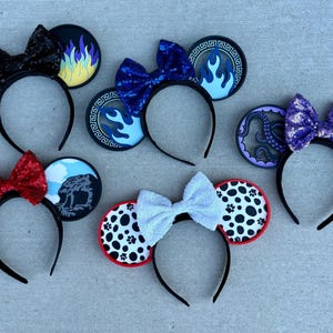 May include: Six themed mouse ear headbands with black headbands and bows. Designs include flames, blue fire, an octopus, Dalmatian spots, and other character-inspired elements. The ears are black with colorful accents.