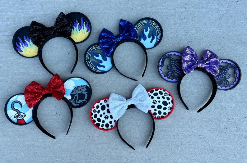May include: Six themed mouse ear headbands with black headbands and bows. Designs include flames, blue fire, an octopus, Dalmatian spots, and other character-inspired elements. The ears are black with colorful accents.