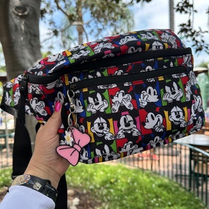 May include: Black fanny pack with a colorful print of Mickey Mouse doing the "See No Evil, Hear No Evil, Speak No Evil" pose. The fanny pack has two zippered compartments and a black strap.