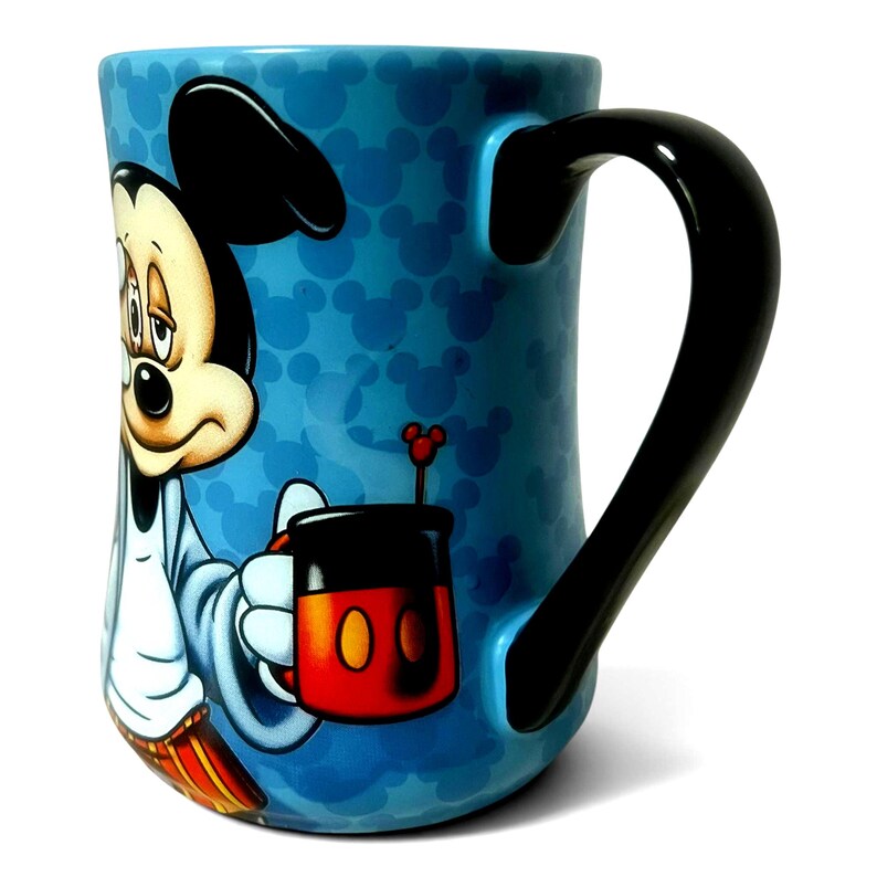 May include: A blue ceramic mug featuring Mickey Mouse. The mug has a black handle and is decorated with Mickey Mouse silhouettes. Mickey Mouse is depicted holding a red and black cup with a yellow circle design. The mug has a glossy finish.