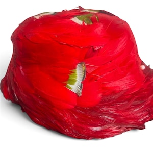 May include: A rounded hat covered in vibrant red feathers. The surface features several small, distinct accents of green and white-tipped feathers arranged in a pattern across the crown and sides. A single small, round, white bead is visible on the side.