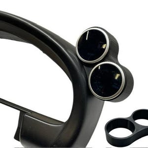 May include: Black automotive gauge pod with two circular gauge openings and a separate dual gauge holder. The pod is designed to mount gauges in a vehicle's dashboard. The gauges have silver trim.