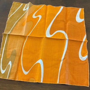 May include: Orange linen fabric with a white and brown abstract design. The fabric has a textured look and feel.