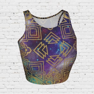 May include: A crop top with a galaxy-themed design. The top features a purple and blue space background with gold geometric patterns. The top has a scoop neck and a racerback style.