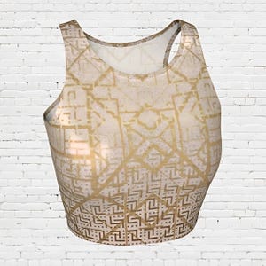 May include: A white tank top with a gold geometric pattern. The tank top is cropped and has a racerback style.