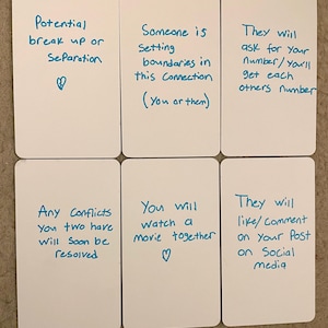 May include: Six white rectangular cards with handwritten blue text. The cards contain phrases such as "Potential break up or Separation" and "They will like/Comment on your Post on Social media". A heart symbol is drawn on two of the cards.