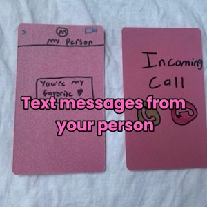 Puede incluir: Dos tarjetas rosas con texto escrito a mano. Una tarjeta dice "Eres mi favorito" y "Mensajes de texto de tu persona". La otra tarjeta dice "Llamada entrante" con un gráfico de teléfono.