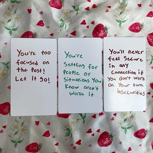 Könnte beinhalten: Drei rechteckige weiße Karten mit handschriftlichem Text. Die erste Karte lautet: You're too focused on the Past! Let it go! Die zweite Karte lautet: You're Settling for People or Situations You Know aren't Worth it. Die dritte Karte lautet: You'll never feel Secure in any Connection if You don't work On Your own insecurities.