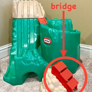 May include: Green and beige plastic playset with a slide, a bridge, and a tunnel. The bridge is covered in red plastic. The playset is made by Little Tikes.