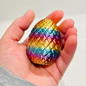 Peut inclure: Un bibelot en forme d'&oelig;uf de dragon aux couleurs de l'arc-en-ciel avec une finition dor&eacute;e. L'&oelig;uf est fait d'un mat&eacute;riau textur&eacute; qui ressemble &agrave; des &eacute;cailles.