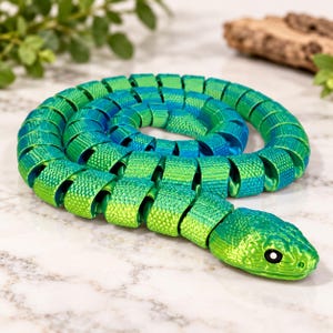 May include: A coiled articulated snake toy featuring a vibrant gradient of metallic green and blue scales. The segmented body has a textured surface with a detailed head, black eyes, and a flexible design that allows it to curl into a circle.